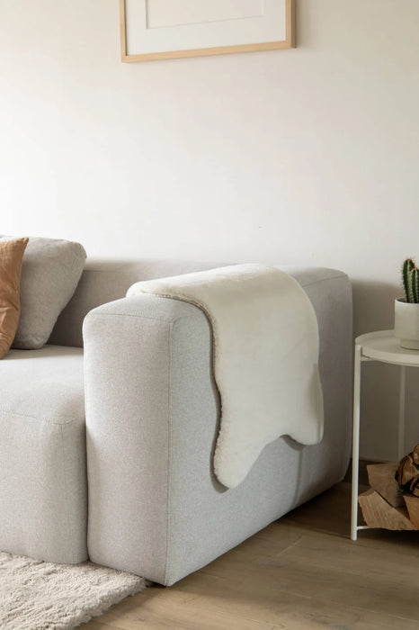 Covor blanita crem pe canapea, decor modern si elegant, ideal pentru living confortabil